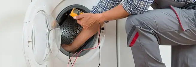 Dryer repair technician inspecting and repairing a clothes dryer in Oakland, CA