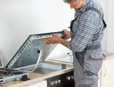 Appliance repair technician installing a built-in cooktop in Oakland, CA