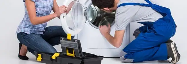 Washer repair technician inspecting a front-load washing machine with tools in Oakland, CA