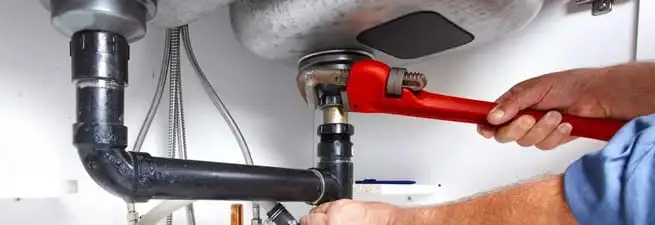 Garbage disposal repair technician tightening the sink drain and disposal connection in Oakland, CA