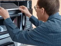 Appliance repair technician replacing a microwave vent filter in Oakland, CA