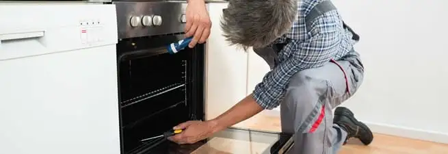 Oven repair technician inspecting and servicing an electric oven in Oakland, CA