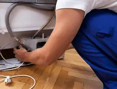 Appliance repair technician fixing refrigerator water line and connections in Oakland, CA