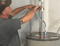 Water heater repair technician tightening supply line connections in Oakland, CA