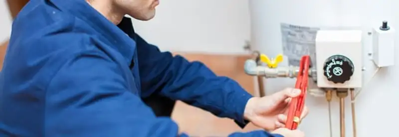 Water heater repair technician adjusting the temperature control and gas valve in Oakland, CA